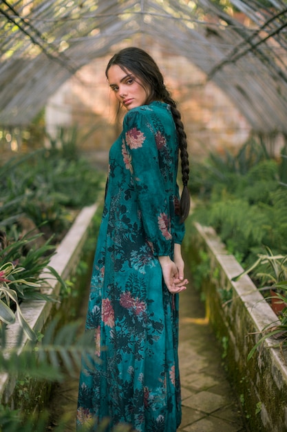 Mujer de lado posando en una casa verde mirando a cámara