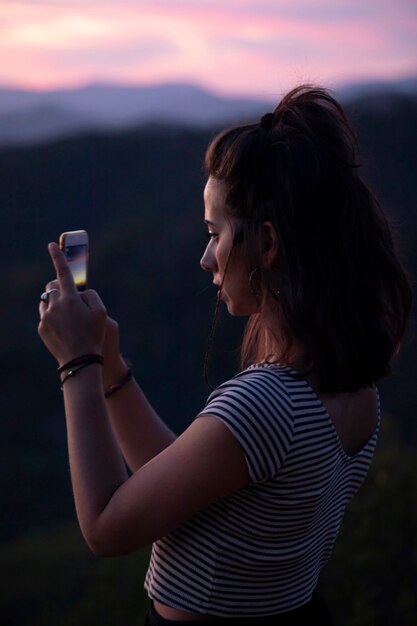 Mujer de lado tomando una foto con su teléfono