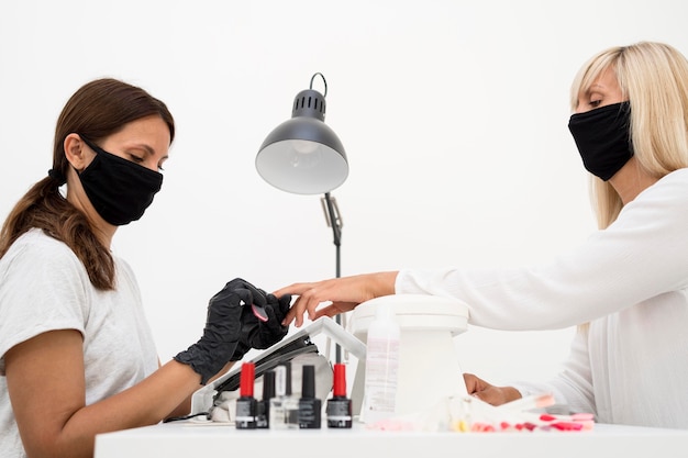 Foto gratuita mujer de lado trabajando en uñas de cliente nuevo normal