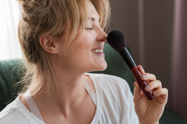 Mujer de lado usando un pincel de maquillaje