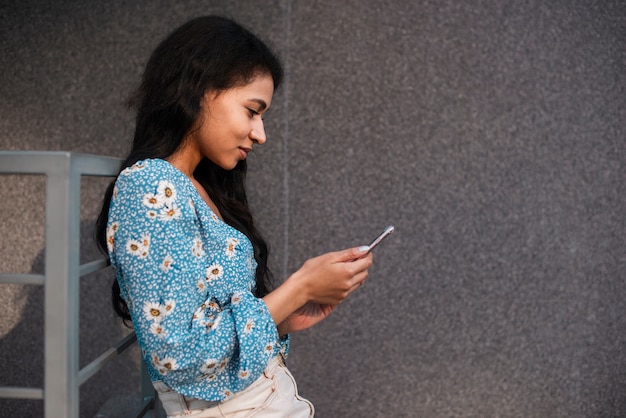 Mujer de lado usando un teléfono inteligente