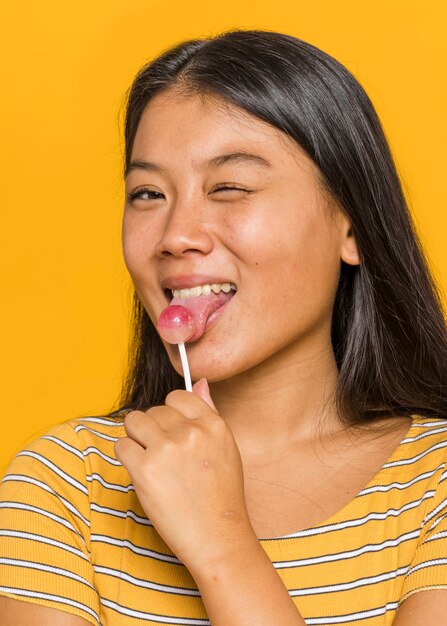 Mujer lamiendo un chupa chups y guiñando un ojo