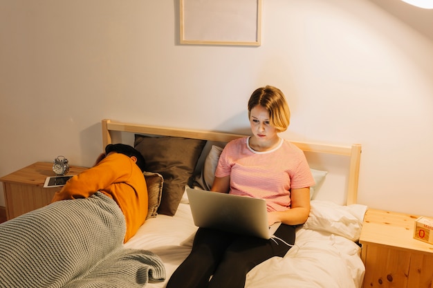 Mujer con laptop cerca de marido durmiente
