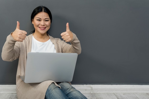 Mujer con laptop mostrando signo ok