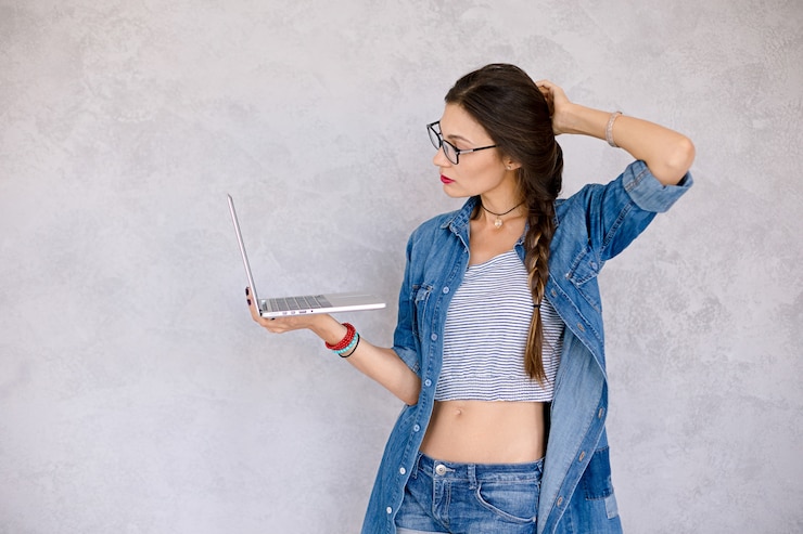 Foto gratuito mujer con laptop toca el cabello con la mano