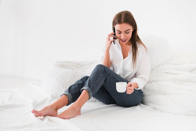 Mujer de larga vista tomando café en la cama