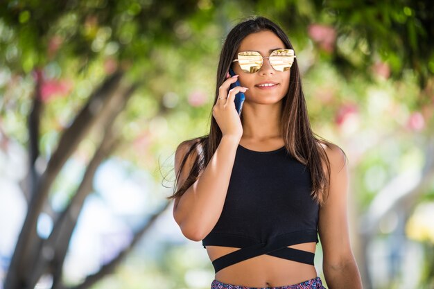 Mujer latina joven hablando por teléfono inteligente en la calle