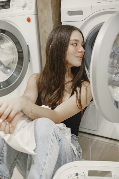 Mujer con lavadora haciendo la colada. Mujer joven dispuesta a lavar la ropa. Interior, concepto de proceso de lavado