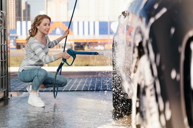 Foto gratuita mujer lavando su coche al aire libre