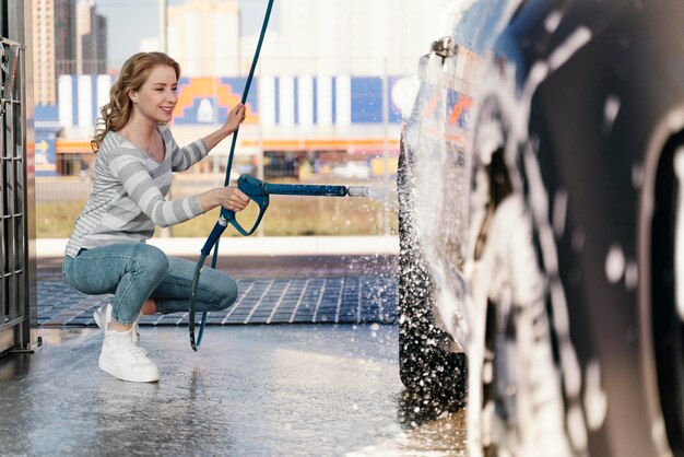 Mujer lavando su coche al aire libre