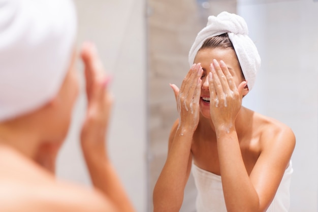 Mujer lavándose la cara en el baño.