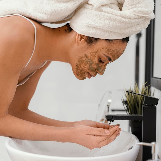 Mujer lavándose la cara después de tener una mascarilla casera