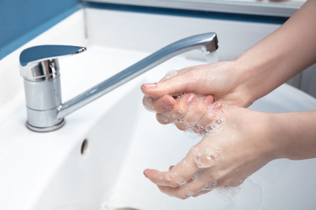 Mujer lavándose las manos cuidadosamente en el baño de cerca la prevención de infecciones