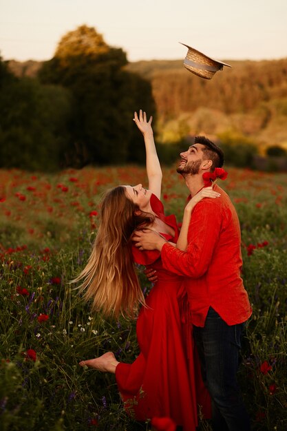 La mujer levanta su sombrero de heno de pie con su hombre en un campo verde