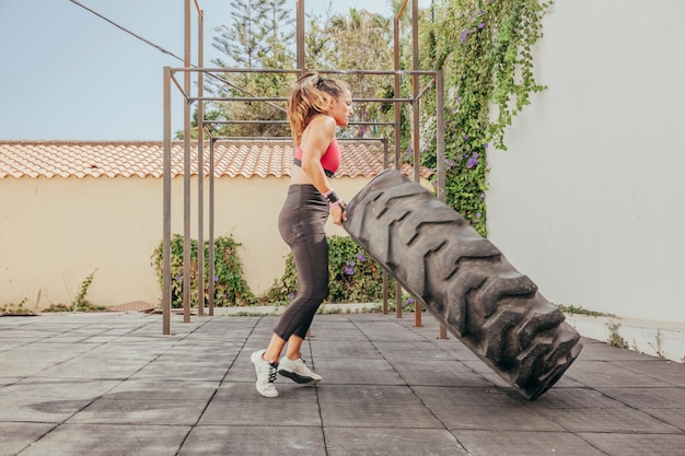 Mujer levantando rueda de tractor