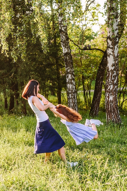 Foto gratuita mujer levantando a su hija en el parque