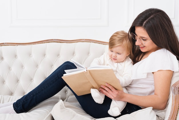 Mujer leyendo con bebé en el sofá