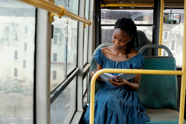 Mujer leyendo en bus plano medio