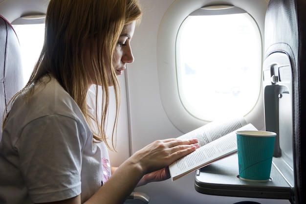 Mujer leyendo un libro en un avión