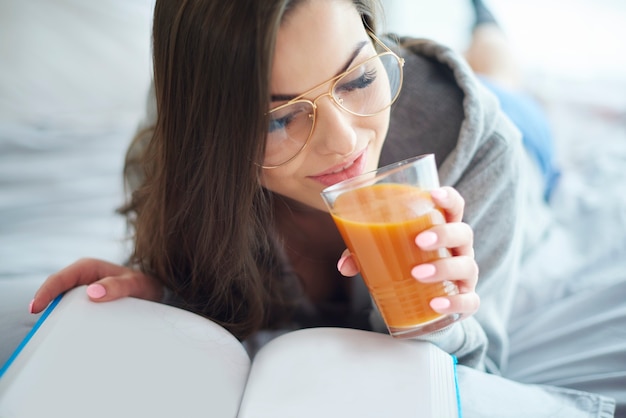 Mujer leyendo libro y bebiendo jugo