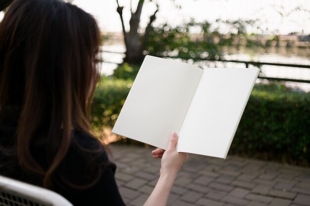 Mujer leyendo el libro en blanco en el jardín