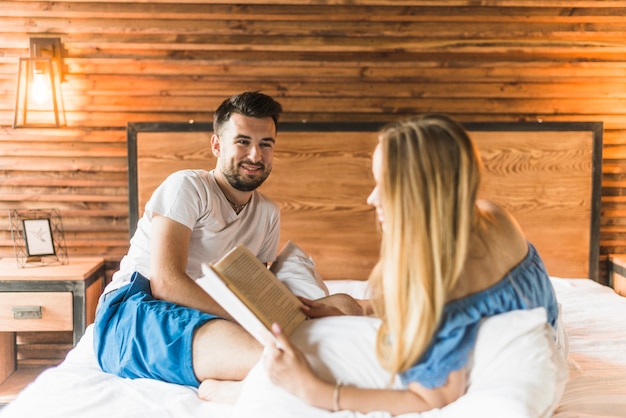 Foto gratuita mujer leyendo el libro de cuentos mientras su sonriente novio la mira