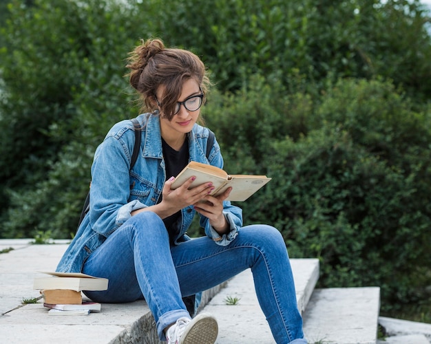 Foto gratuita mujer leyendo el libro en las escaleras del parque