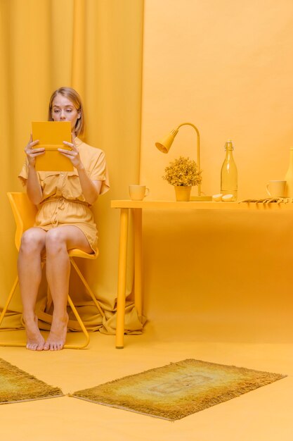 Mujer leyendo un libro en escenario amarillo