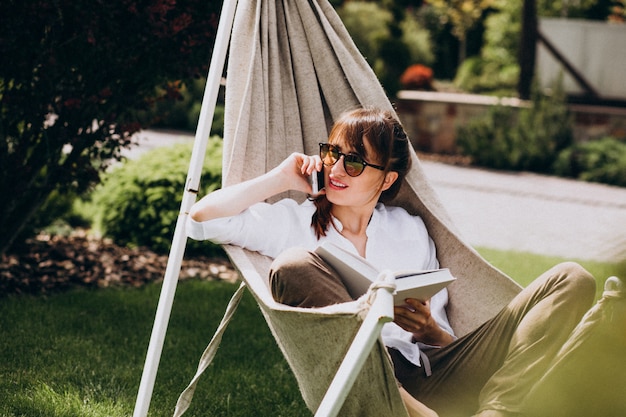 Mujer leyendo un libro en el jardín junto a la casa