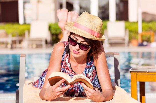 Mujer leyendo un libro mientras está tumbada en una hamaca