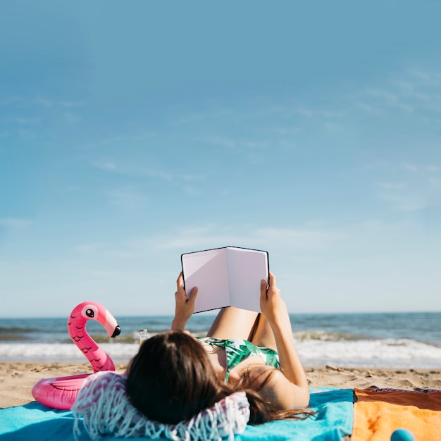 Foto gratuita mujer leyendo libro en la playa