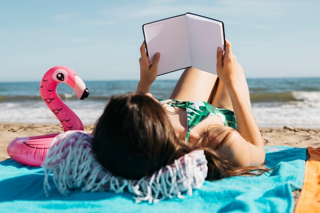 Mujer leyendo libro en la playa