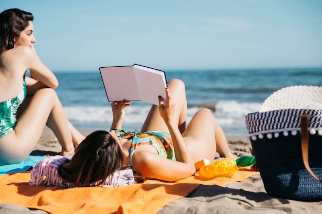 Foto gratuita mujer leyendo libro en la playa