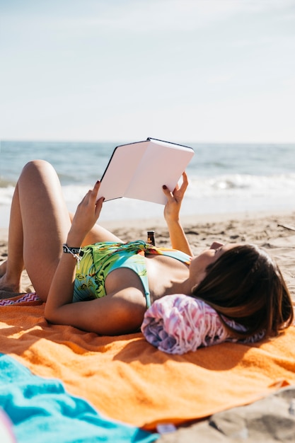 Mujer leyendo libro en la playa