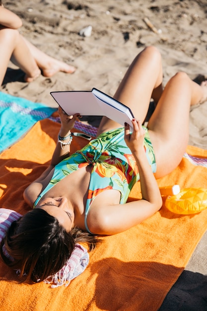 Mujer leyendo libro en la playa