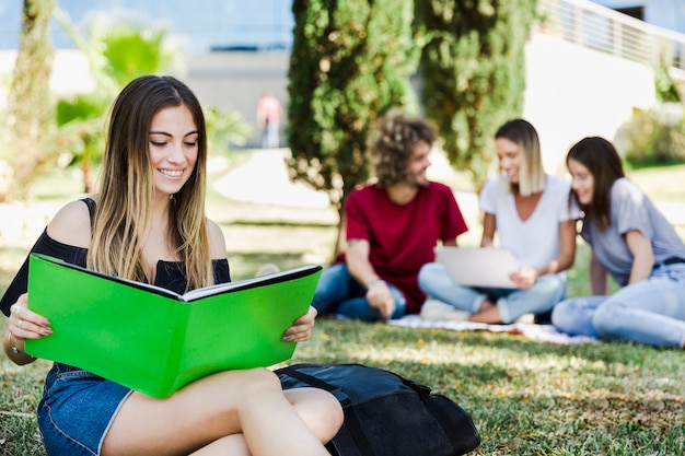 Mujer leyendo el libro de texto en la hierba