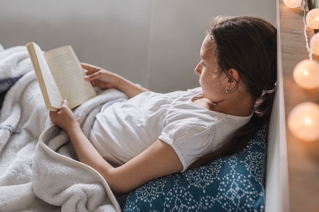 Foto gratuita mujer leyendo mientras está en la cama