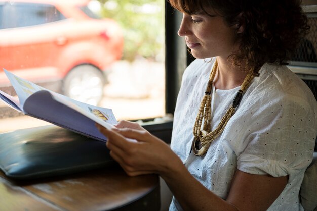 Mujer leyendo la revista en la cafetería