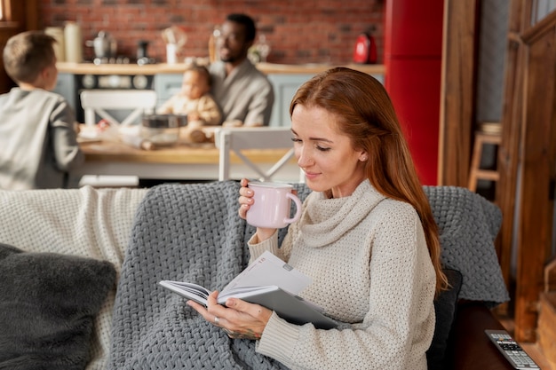 Foto gratuita mujer leyendo en el sofá de tiro medio