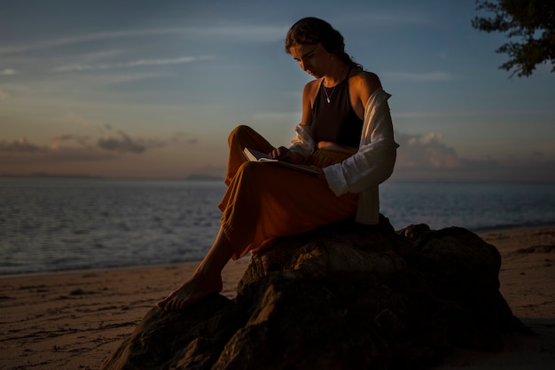 Mujer leyendo en la vista lateral de la playa