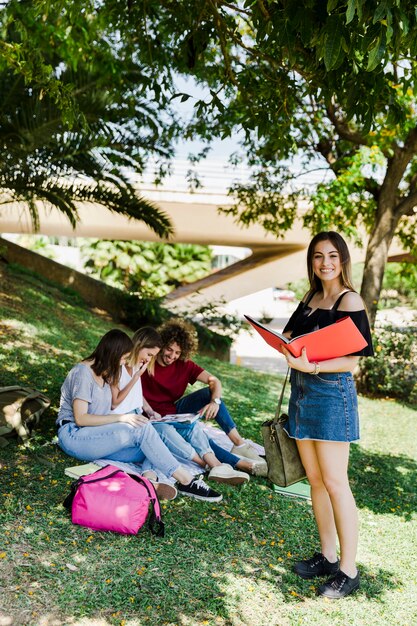 Mujer con libro abierto en el parque con amigos