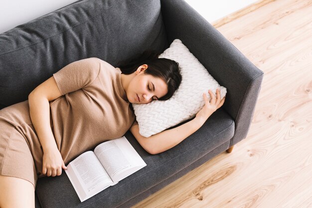 Mujer con libro durmiendo en el sofá