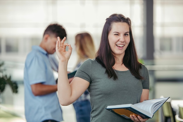 Foto gratuita mujer con libro gesticular bien