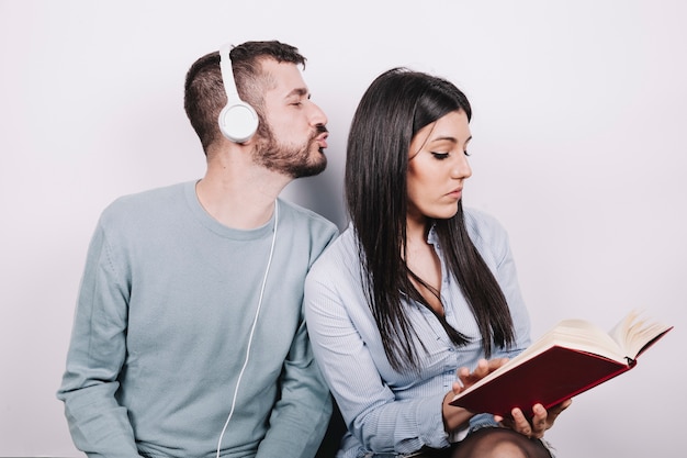 Foto gratuita mujer con libro ignorando hombre en auriculares