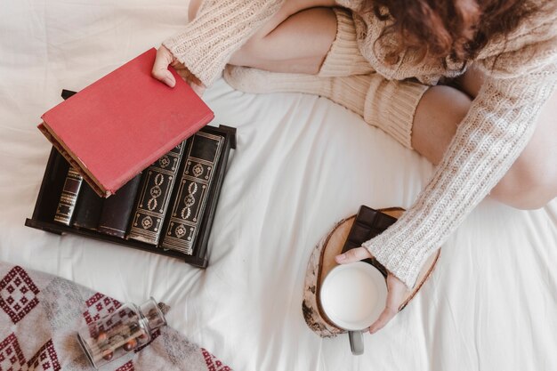 Mujer con libro y leche en la cama