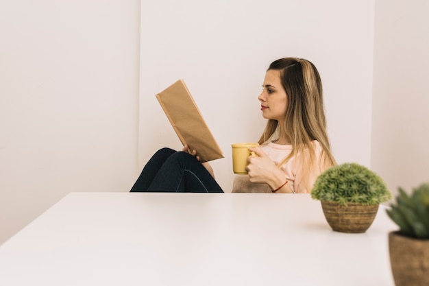 Foto gratuita mujer con libro de lectura de taza