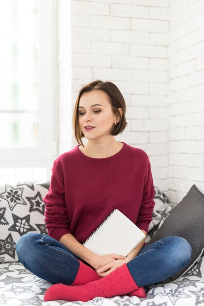 Mujer con libro en la mano esperando en el sofá