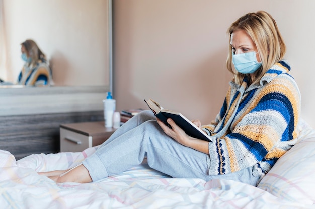 Mujer con libro y mascarilla médica en cuarentena