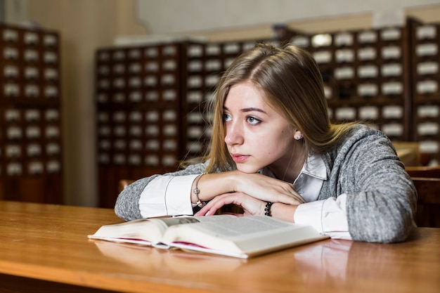 Foto gratuita mujer con libro en el mostrador de la biblioteca