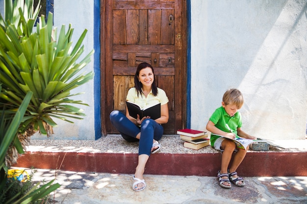 Foto gratuita mujer con el libro y el niño en el pórtico